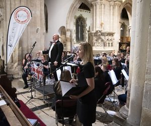 Band conductor Simon with band and singer performing at Wimborne Minster