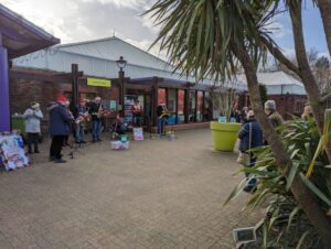 Band members busking outside garden centre with audience