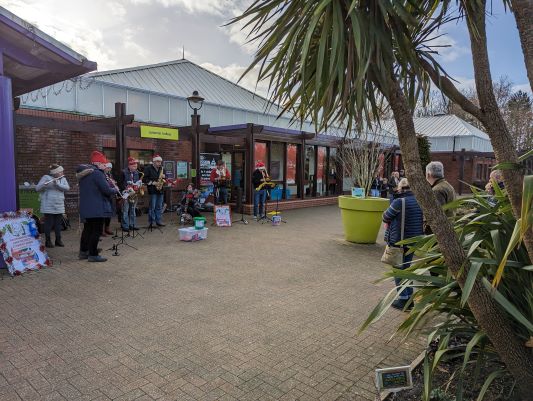 Band members busking outside garden centre with audience